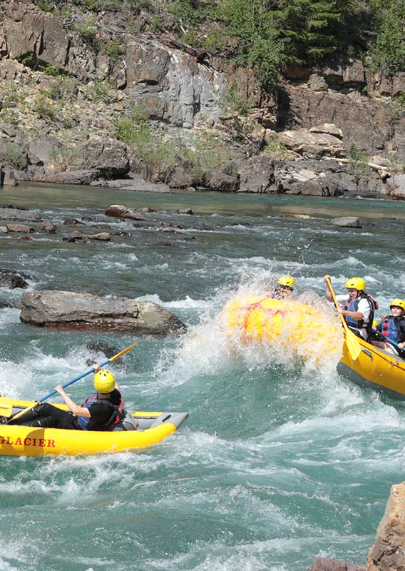 Two groups of people in a kayak and raft in white water.