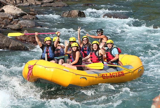 A group of people on a big yellow raft on a wide river.
