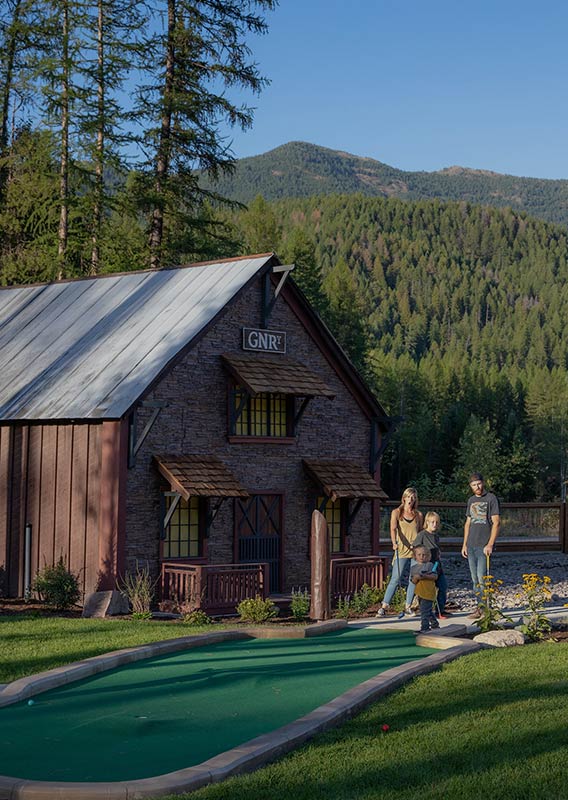 A family stands outside on a mini-golf area.