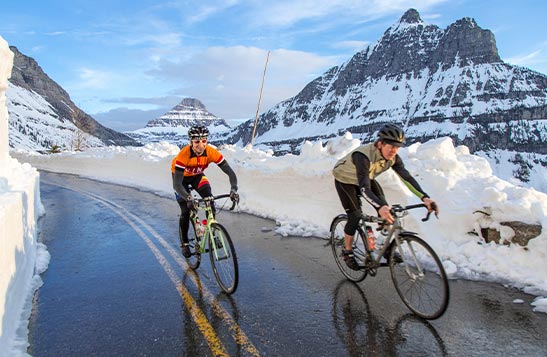 cyclists on a narrow road next to tall cliffsides. A wooden hotel entrance.