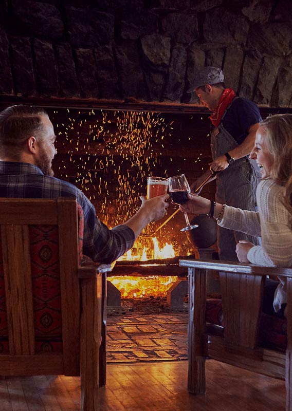 Glacier Park Lodge Lobby fireplace burns behind romantic cheers between couple