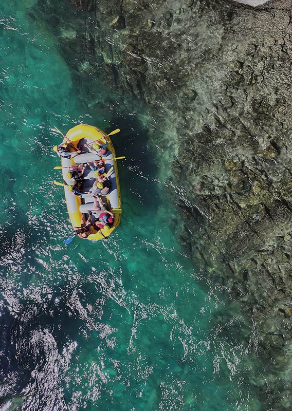 A bird's eye view of a group of people in a yellow raft in clear water.