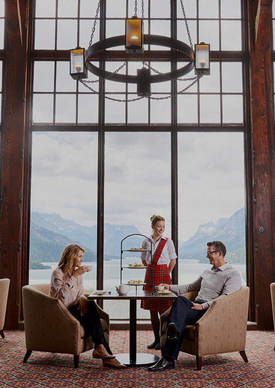 A couple sitting for Afternoon Tea overlooking Upper Waterton Lake