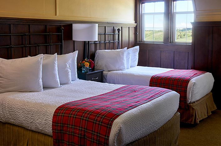 Well-appointed hotel room with one twin and one double bed and mountain views