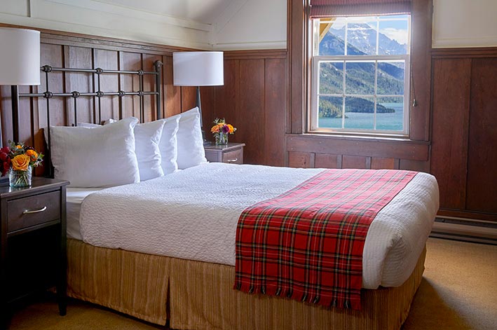 Well-appointed hotel room with one queen bed and views of Waterton Lake