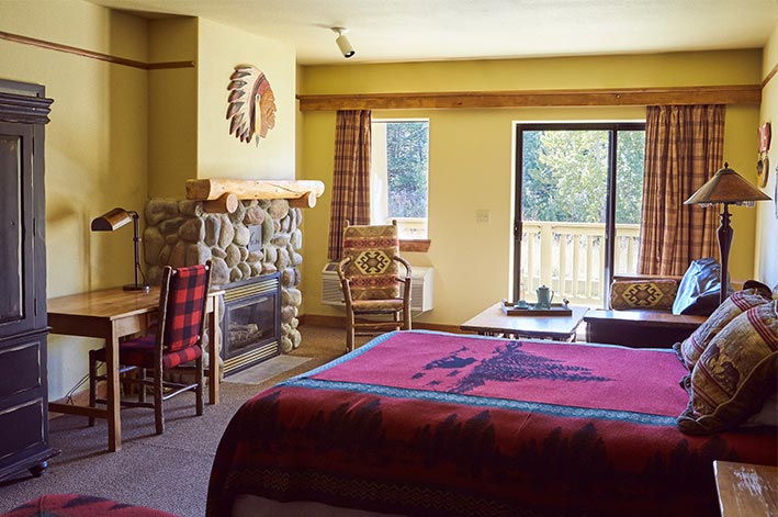 Great Bear Lodge Superior Room at St. Mary Village featuring a river rock fireplace and sitting area