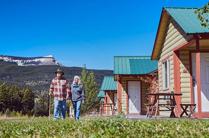 Couple walking in the grass outside the Glacier Cabins at St. Mary Village