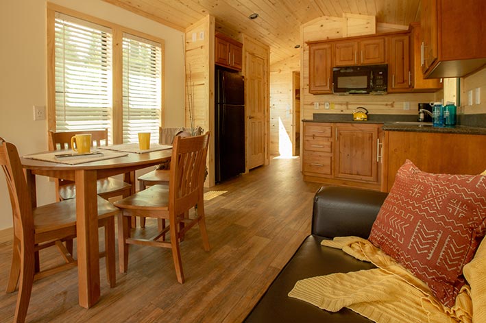 A table and couch inside a wooden cabin.