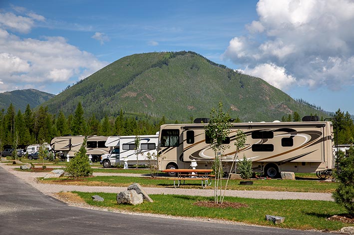 a view of several RVs parked at camp sites with picnic tables