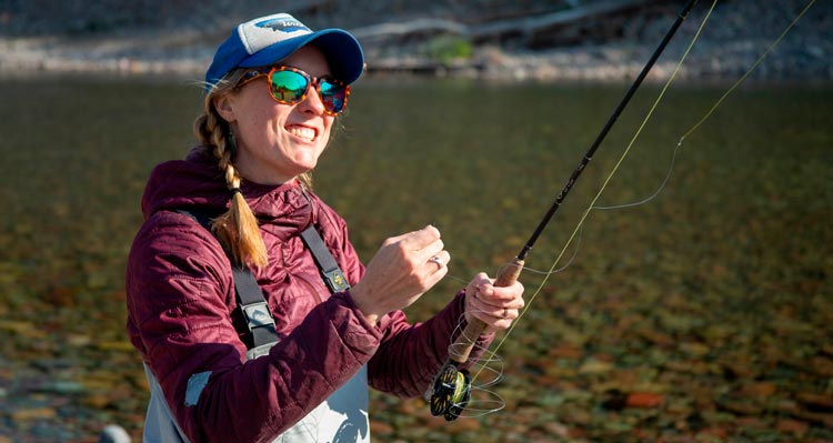 A woman holds a fishing rod and smiles in excitment.