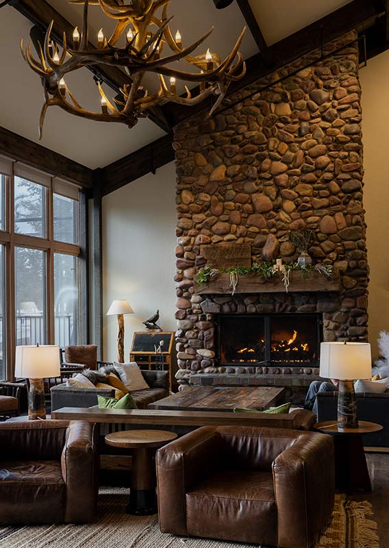 A hotel lobby with leather chairs and a tall stone fireplace.