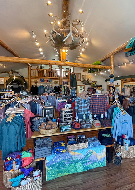 The interior of a shop with lots of outdoor goods on racks and tables.