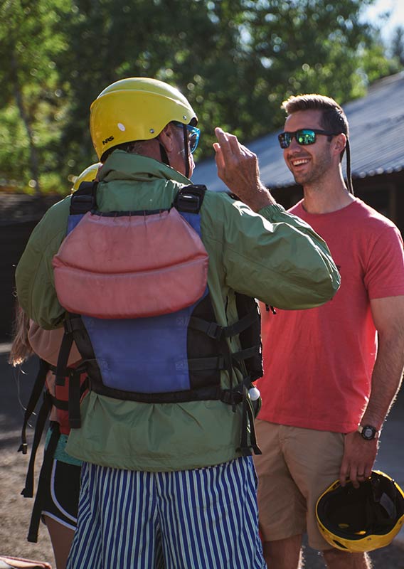 A guide shows two guests how to put on their safety gear.