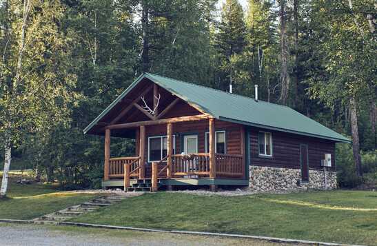 Exterior of a cabin next to a conifer forest.