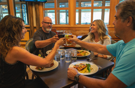 People raising their glasses together across a table with beer