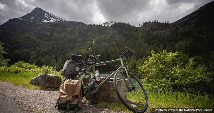 A bike parked against a rock in front of a mountain view